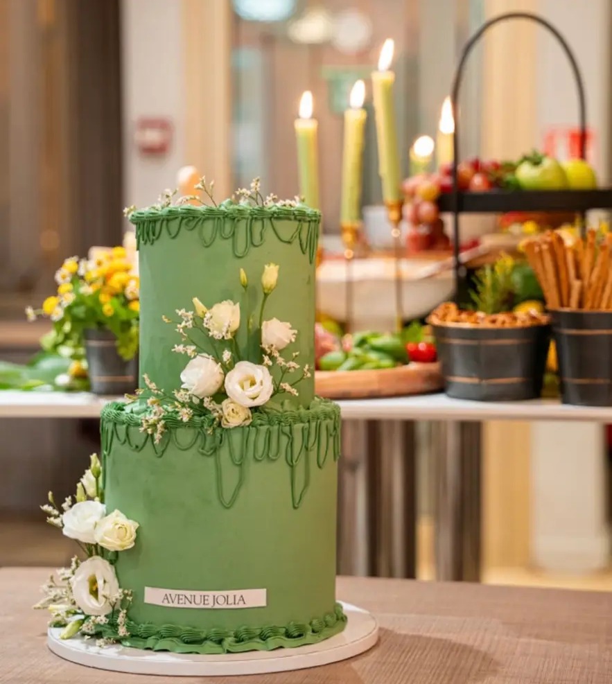 Layer cake vert décoré de fleurs blanches et d'un glaçage coulant